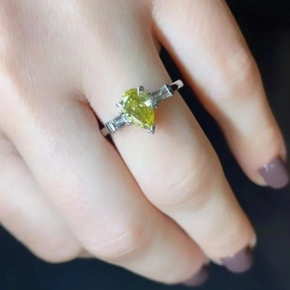 Engagement ring in white gold set with pear-cut Fancy Deep Greenish Yellow (1.11 ct).