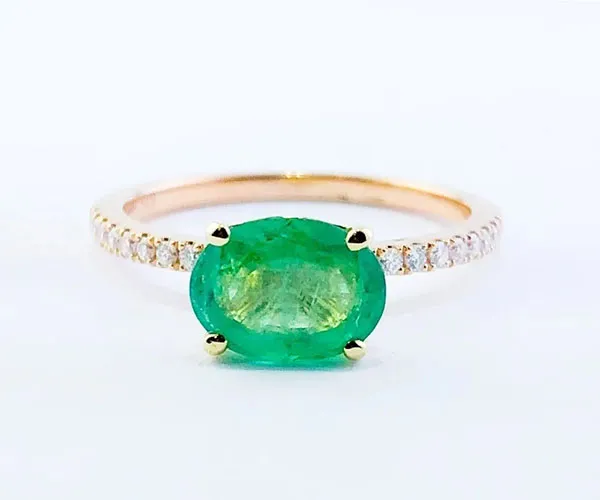 Ring in rose gold set with oval-cut emerald and brilliant-cut diamonds.